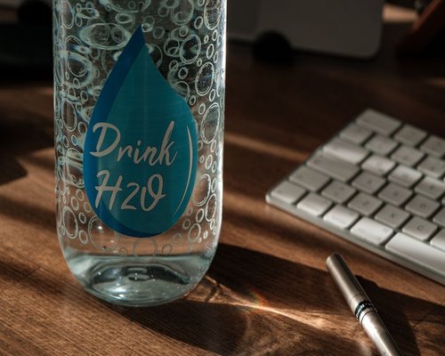 Person drinking water from a reusable bottle while working at a desk